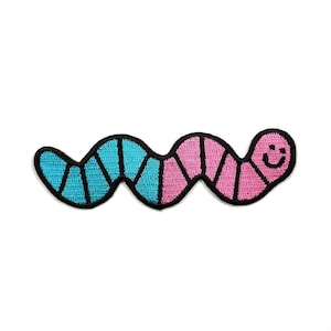 May include: An embroidered patch shaped like a segmented worm with a smiling face. The worm features alternating sections of bright blue and pink thread, all outlined with a thick black border. The design is flat and has a textured fabric finish.