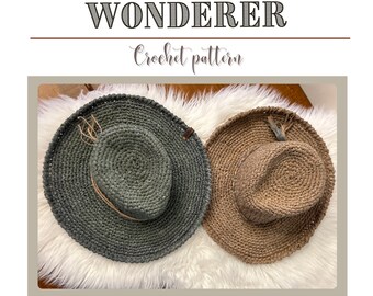 May include: Two crocheted hats, one in a dark green color and one in a light brown color, are displayed on a white fluffy surface. The hats are both wide-brimmed and have a simple design. The text "The Wainscott Wanderer Crochet Pattern" is displayed above the hats.