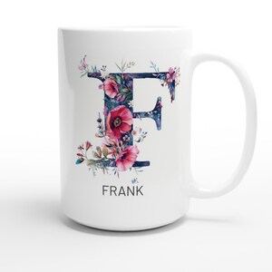 Può includere: Tazza in ceramica bianca con un design floreale che presenta la lettera "F" e il nome "FRANK" stampato sotto.