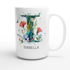 May include: White ceramic mug with a floral design featuring the letter I and the name Isabella. The letter I is surrounded by colorful flowers and leaves.