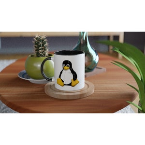 Può includere: Una tazza in ceramica bianca con bordo e manico neri. La tazza presenta un pinguino dei cartoni animati con corpo nero, pancia bianca e becco e piedi gialli. Il pinguino è seduto su uno sfondo bianco.