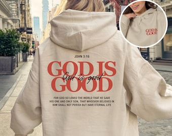 May include: A sand-colored hooded sweatshirt featuring red text on the back that reads JOHN 3:16 GOD IS GOOD, with the phrase God is good in black script and the full Bible verse below. A circular inset shows the front with red text GOD IS GOOD.
