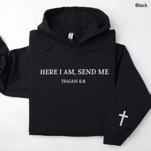 May include: Black hooded sweatshirt with white text that reads "HERE I AM, SEND ME" and "ISAIAH 6:8". A white cross is on the left sleeve. The sweatshirt has a drawstring hood and a front pocket.