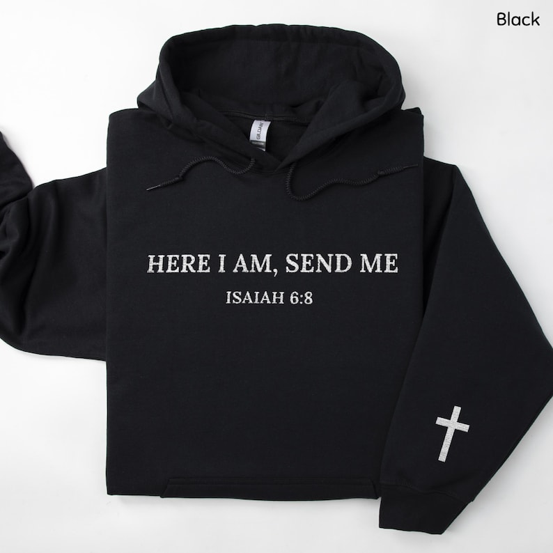 May include: Black hooded sweatshirt with white text that reads "HERE I AM, SEND ME" and "ISAIAH 6:8". A white cross is on the left sleeve. The sweatshirt has a drawstring hood and a front pocket.