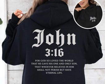 May include: A black hoodie featuring white text on the back that reads John 3:16 followed by the full verse. The front chest area displays a smaller white graphic with the text John 3:16. The garment includes a hood and long sleeves.