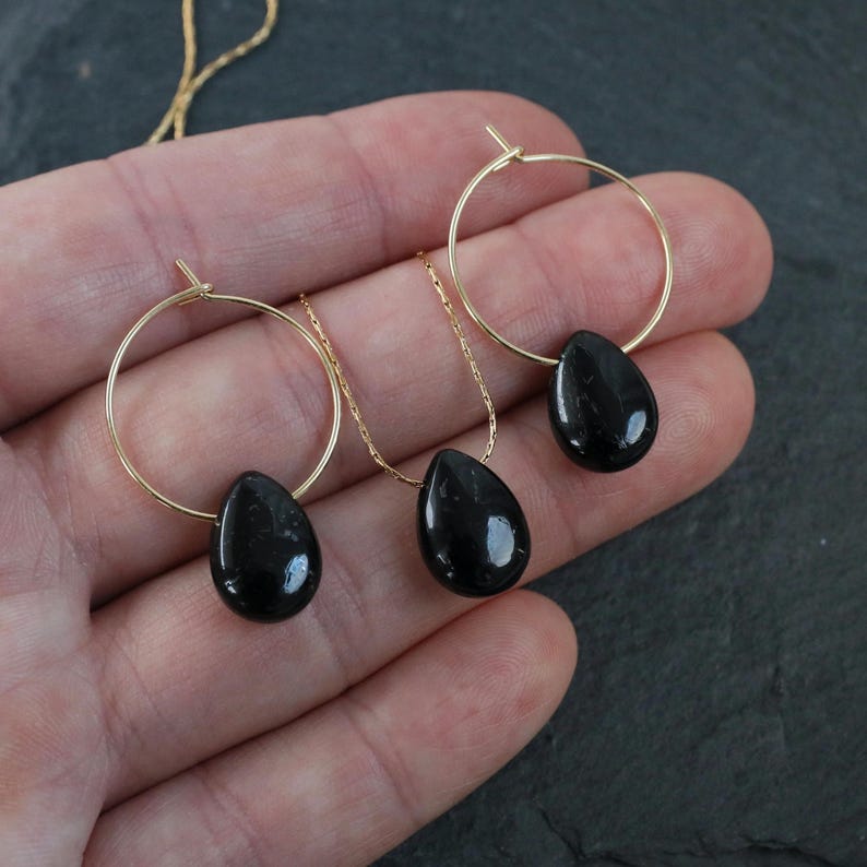 May include: A set of black gemstone earrings and a necklace with gold hoops and chains. The gemstones are teardrop shaped.