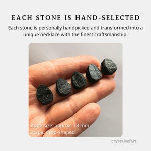 May include: The image displays five drop-shaped, black stones, each approximately 13 mm in size, resting on a hand. The text reads "EACH STONE IS HAND-SELECTED" and describes the stones as being handpicked and transformed into unique necklaces.