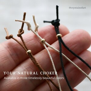 May include: Close-up of three natural chokers in brown, off-white, and black. Each choker features a small gold bead and is knotted at the top. The text "YOUR NATURAL CHOKER" is visible at the bottom of the image.