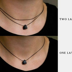 Puede incluir: Collares con colgantes de piedra negra. La imagen muestra dos estilos de collar: un dise&ntilde;o de dos capas y uno de una sola capa. Los collares presentan un colgante de piedra oscura suspendido de un fino cord&oacute;n negro. El texto "TWO LAYER" y "ONE LAYER" es visible.