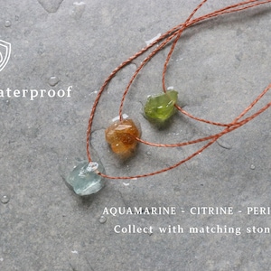 Puede incluir: Tres collares de piedras preciosas con piedras de aguamarina, citrino y peridoto sobre cordones marrones. La imagen incluye el texto "Waterproof" y los nombres de las piedras preciosas. Los collares se muestran sobre una superficie gris.