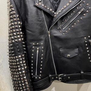 Puede incluir: Una chaqueta de cuero negra para motocicleta con tachuelas piramidales de metal plateado que cubren toda la manga y las solapas. La chaqueta incluye una cremallera frontal diagonal, varios bolsillos con cremallera, un bolsillo peque&ntilde;o con solapa y un cintur&oacute;n.
