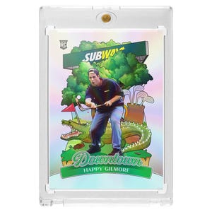 May include: A trading card featuring a cartoon illustration of a man playing golf with a crocodile. The card has the Subway logo and the words "Downtown Happy Gilmore". The card is encased in a clear plastic holder.