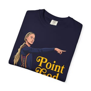 Può includere: Una t-shirt blu navy con un'illustrazione grafica di un'atleta bionda con coda di cavallo che indica di lato. Il design include una striscia verticale con stelle sul lato della maglia e il testo giallo Point God posizionato sotto.