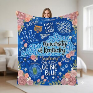 Puede incluir: Una manta azul de la Universidad de Kentucky con gráficos florales y temáticos de Kentucky. La manta presenta el texto "University of Kentucky", "Go Big Blue" y "Sydney Class of 2026". Está decorada con rosas, huellas de patas y una bola de discoteca.