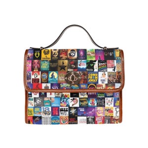 Könnte beinhalten: Eine strukturierte Handtasche mit einer Collage aus verschiedenen Broadway-Musical-Plakaten auf der Oberfläche. Die Tasche hat braune Lederbesätze, einen einzelnen Tragegriff und einen zentralen metallischen Drehverschluss. Der bunte Druck zeigt zahlreiche Titel.