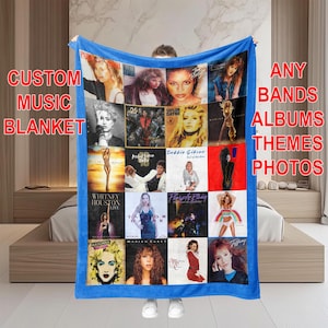 May include: A blue fleece blanket with a collage of various music artists and album covers. The blanket features images of Whitney Houston, Taylor Dayne, Debbie Gibson, Madonna, and Tiffany. The text "CUSTOM MUSIC BLANKET" is at the top left corner of the blanket. The text "ANY BANDS ALBUMS THEMES PHOTOS" is at the top right corner of the blanket.