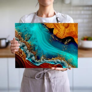 Könnte beinhalten: Abstrakter Kunstdruck mit einer auffälligen Mischung aus Türkis-, Gold- und Brauntönen. Das Kunstwerk zeigt fließende, wirbelnde Muster mit goldenen Akzenten, die einen dynamischen und strukturierten visuellen Effekt erzeugen. Das Stück wird von einer Person gehalten.