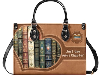 Puede incluir: Un bolso de mano de cuero marrón con un diseño en forma de corazón que presenta una pila de libros antiguos. El bolso tiene un asa negra y una correa negra. El texto "Just one more Chapter" está impreso en la parte delantera del bolso.