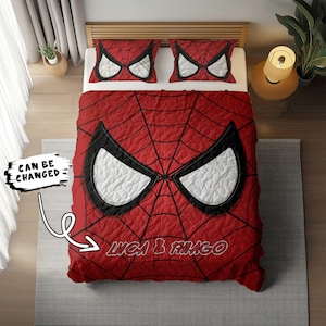 Peut inclure: Une couette rouge et noire sur le thème de Spiderman avec un motif de toile d'araignée blanche. La couette est accompagnée de deux taies d'oreiller assorties avec un visage de Spiderman. La couette porte le texte "Luca & Thiago".