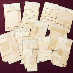 May include: A set of 11 vintage-style paper cards with lace trim. The cards are made of a cream-colored paper and have a distressed look. They are perfect for scrapbooking, card making, or other crafting projects.