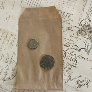 May include: A brown paper envelope with two US coins inside. The coins are a quarter and a dime.