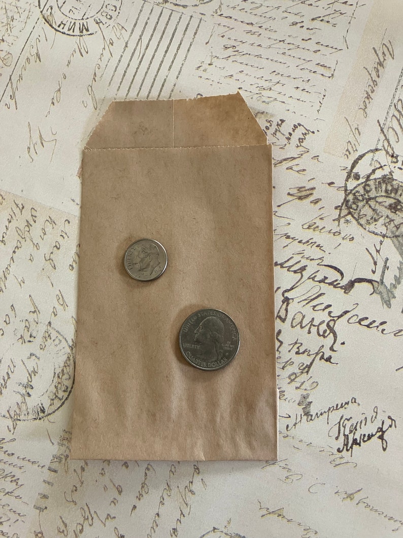 May include: A brown paper envelope with two US coins inside. The coins are a quarter and a dime.