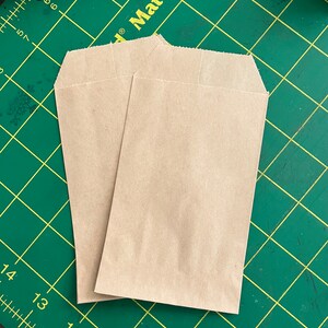 May include: Two brown paper bags on a green cutting mat with white markings.