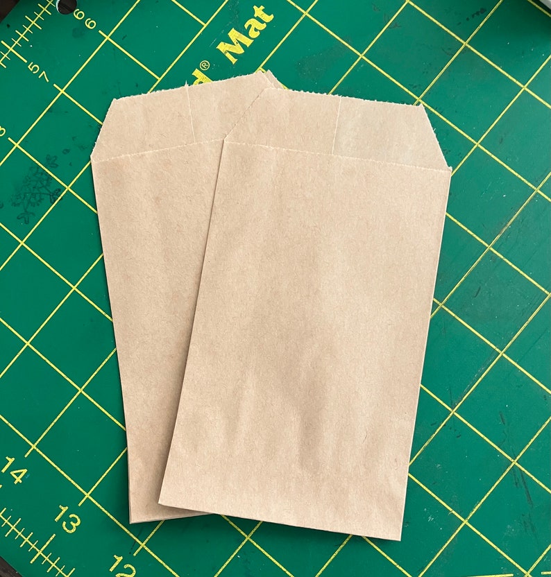 May include: Two brown paper bags on a green cutting mat with white markings.