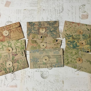 May include: Nine vintage-style envelopes with floral patterns and brown paper. Each envelope has a brown button and twine tied around it.