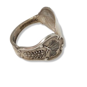 May include: Silver spoon ring with a pine tree design. The ring is made from a bent spoon and has the words "G.S. COONLEY" engraved on the inside.