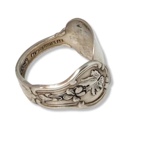 May include: A silver spoon ring with a floral design. The ring is marked "STERLING 925" and "RHODE".