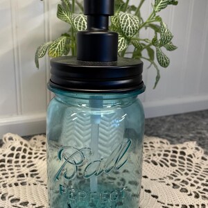 May include: A blue glass soap dispenser with a black pump and lid. The glass jar has the words "Ball Perfect Mason" printed on it.