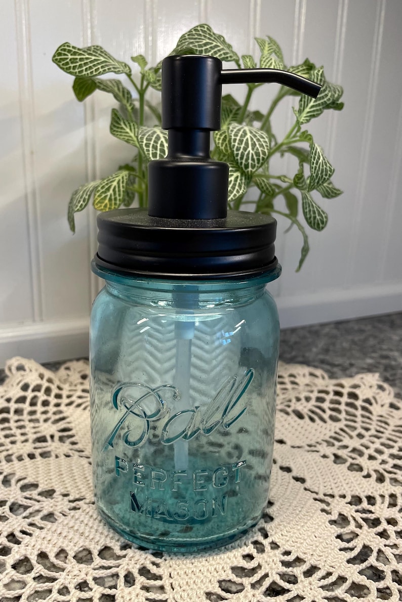 May include: A blue glass soap dispenser with a black pump and lid. The glass jar has the words "Ball Perfect Mason" printed on it.