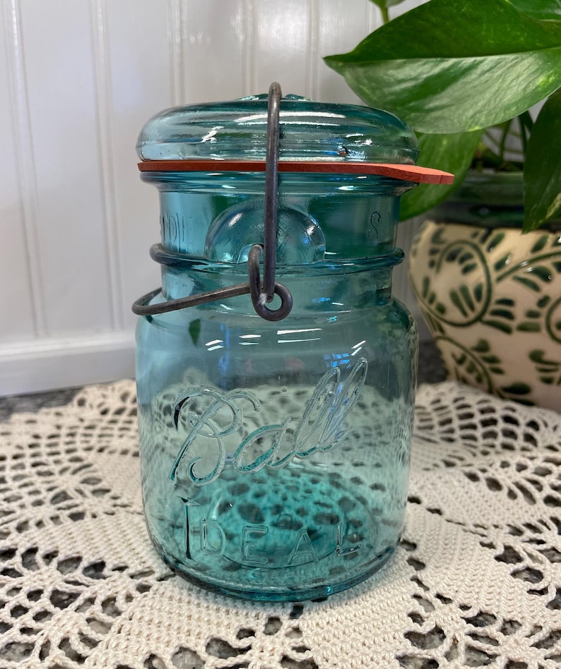 May include: A vintage blue glass Ball Ideal jar with a wire bail closure and a red rubber lid.