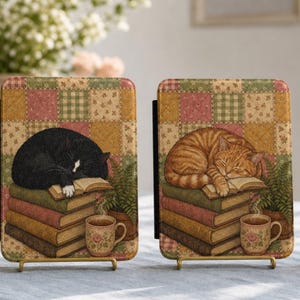 May include: Three rectangular e-reader covers featuring a patchwork quilt background. Each cover displays a sleeping cat resting on a stack of books next to a steaming floral mug. The cats are black, orange tabby, and calico, respectively.