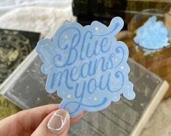 May include: Blue sticker with the text "Blue means you" in white cursive lettering. The sticker has a light blue background with white stars and a constellation design.