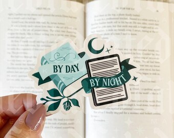 Op de afbeelding: Een sticker met een groen en blauw ontwerp met twee boeken. Het bovenste boek heeft de tekst "By Day" en het onderste boek heeft de tekst "By Night".