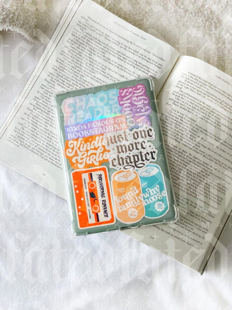Pu&ograve; includere: Una custodia per telefono verde con vari adesivi colorati. Gli adesivi presentano frasi come "Chaos Readers", "Kinda Famous on Bookstagram", "Just One More Chapter" e "Found Family Why Moose".