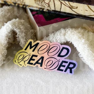 May include: A sticker with a rainbow gradient background and the text "Mood Reader" in black.