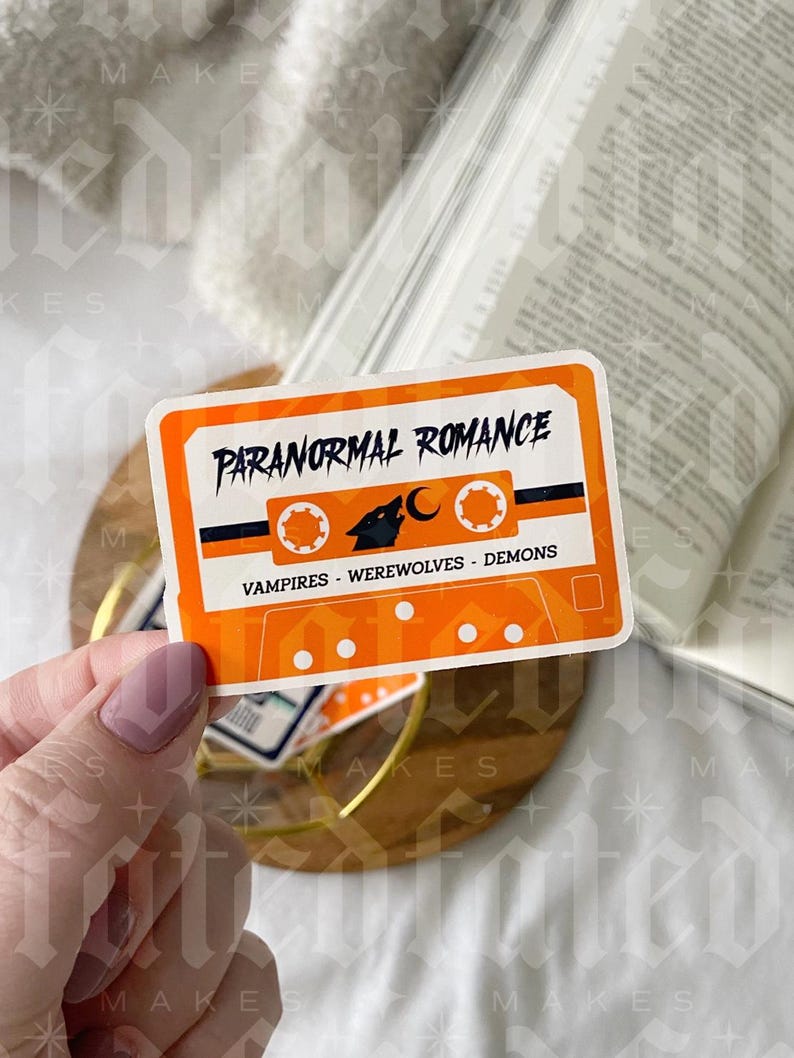Pu&ograve; includere: Sticker a forma di cassetta arancione e nero con il testo "Paranormal Romance" e "Vampires - Werewolves - Demons".