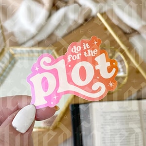 May include: A pink and orange gradient sticker with the text "do it for the plot" in white. The sticker has a sparkly finish and is being held by a hand.
