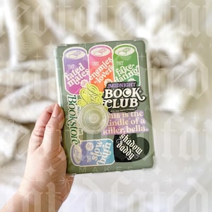 May include: A green book club journal with stickers on the cover. The stickers are colorful and have text that reads "fated mates", "enemies to lovers", "fake hating", "Bookstore", "slow burn", "shadow daddy", and "MIDNIGHT BOOK CLUB".
