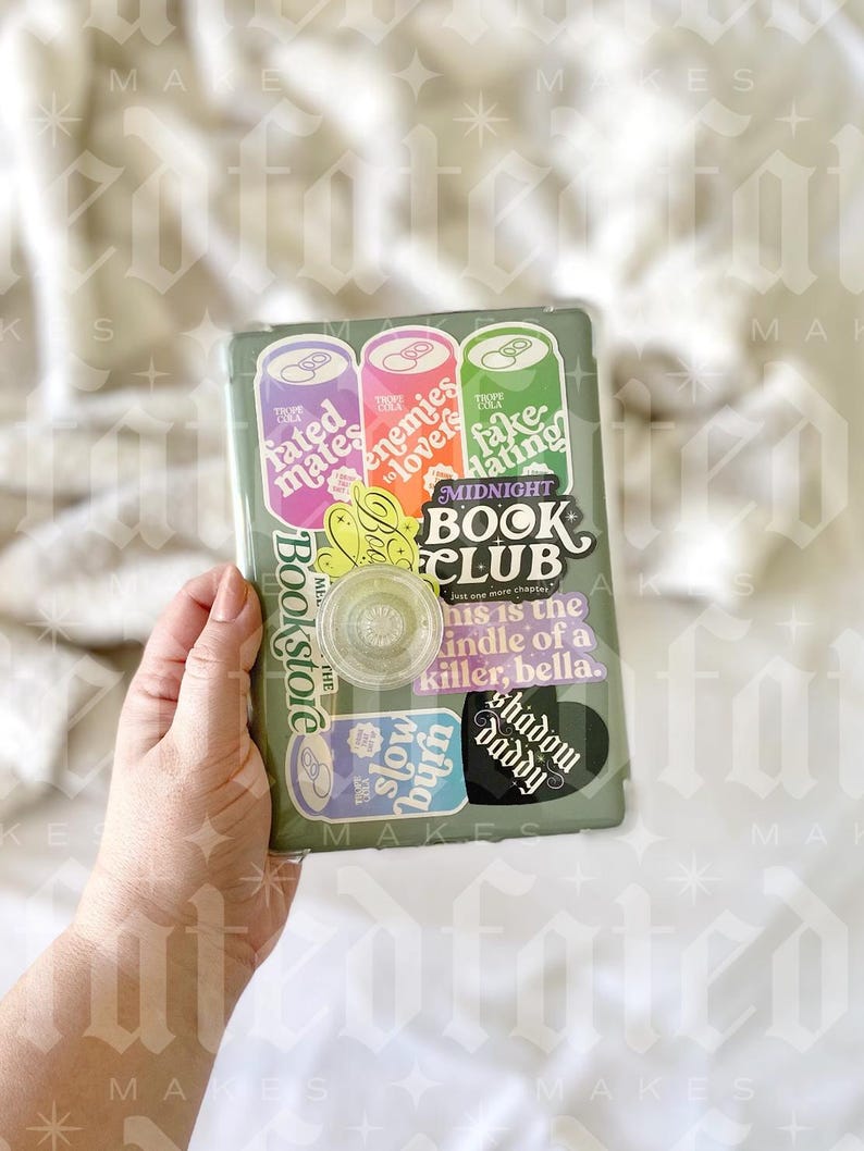 May include: A green book club journal with stickers on the cover. The stickers are colorful and have text that reads "fated mates", "enemies to lovers", "fake hating", "Bookstore", "slow burn", "shadow daddy", and "MIDNIGHT BOOK CLUB".
