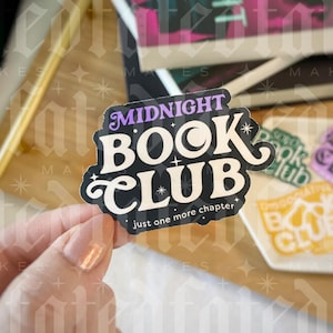 May include: A black and white sticker with the text "Midnight Book Club" in a stylised font. The sticker has a purple crescent moon and stars. The text "just one more chapter" is printed below the main text.