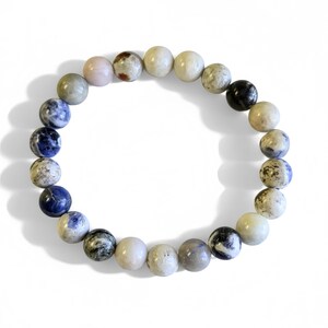May include: A beaded bracelet with a mix of blue, white, and gray stones. The bracelet is made of round beads with a smooth finish.