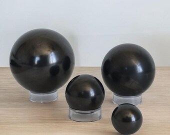 May include: Four black obsidian spheres of varying sizes on clear acrylic stands. The spheres are smooth and polished.