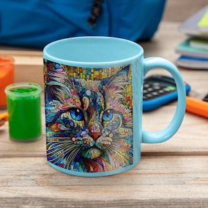 May include: A light blue ceramic mug with a colorful mosaic cat design. The cat's eyes are blue and the design is made up of small, colorful squares.