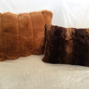 May include: Two decorative throw pillows. One is a light brown color with a ribbed design. The other pillow is a darker brown with a textured appearance. Both pillows have a soft, plush texture and are rectangular in shape.