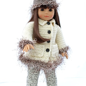 May include: A doll wearing a crocheted cream-colored coat with brown fur trim, brown crocheted pants, and a brown crocheted hat with a white fur trim.