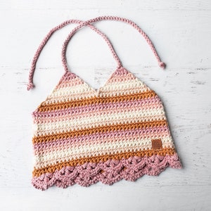 May include: A crocheted halter top with a pink, white, and orange striped pattern. The top has a scalloped hem and a brown leather label.